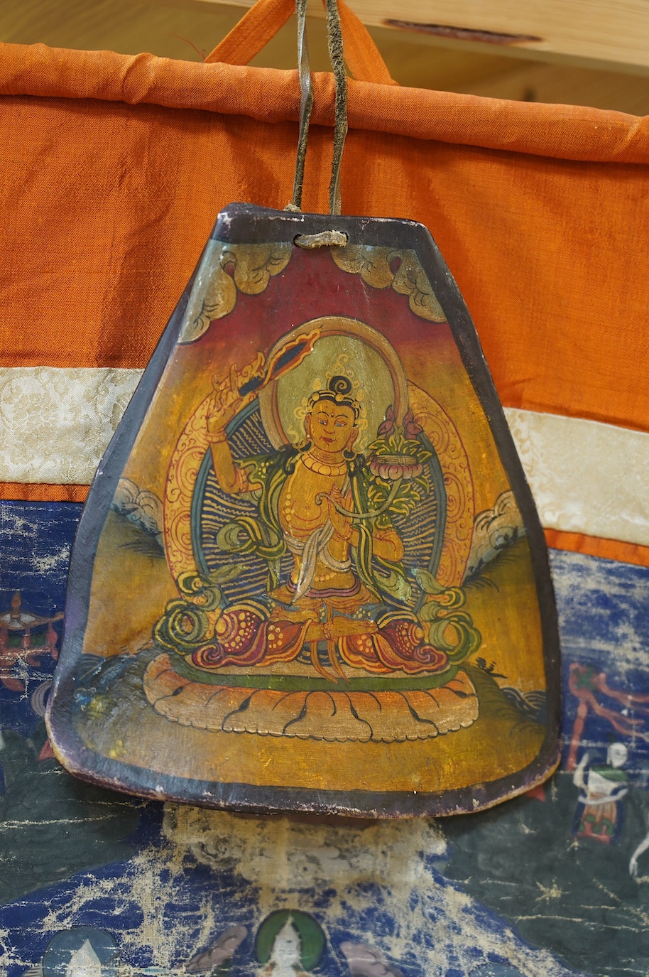 A Tibetan painted silk thangka and another painted on an ox bone, both 19th century. Condition - poor to fair